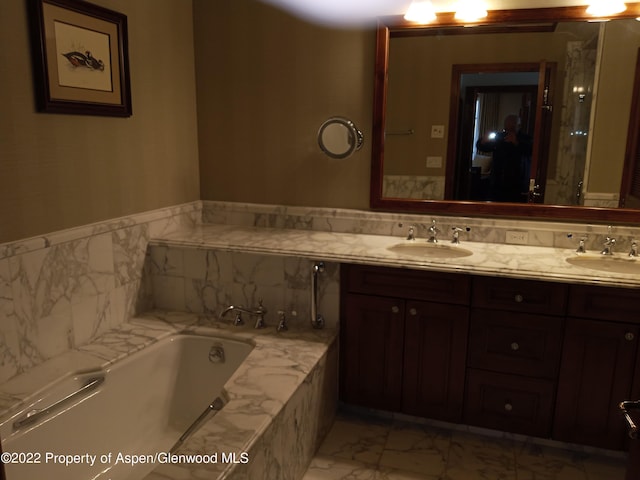 bathroom with tiled tub and vanity