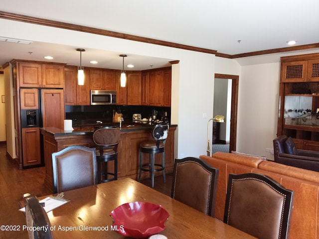 dining space featuring sink, ornamental molding, and dark wood-type flooring