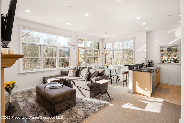 living room with a notable chandelier, light hardwood / wood-style floors, and sink