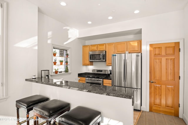 kitchen with kitchen peninsula, stainless steel appliances, and a breakfast bar