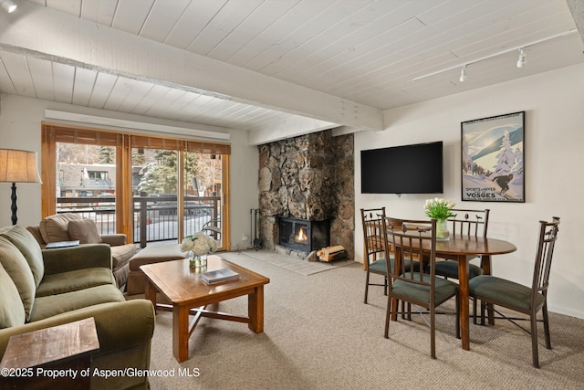 131 E Durant Ave Unit 104, Aspen, CO 81611 - living room with light carpet, wood ceiling with exposed beams, and a stone fireplace