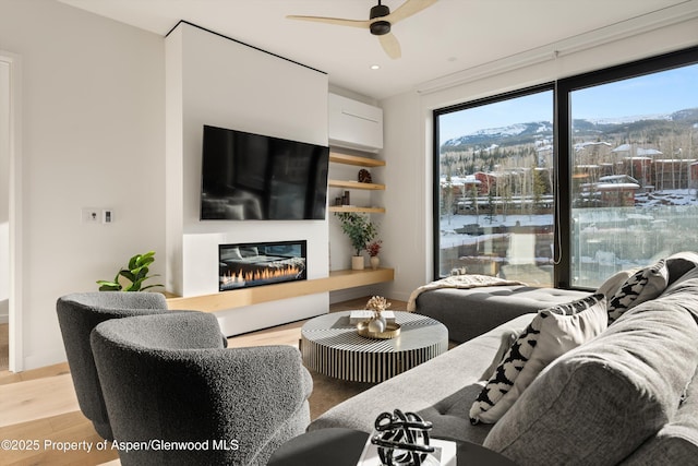 living room with a wall mounted AC, ceiling fan, and light wood-type flooring