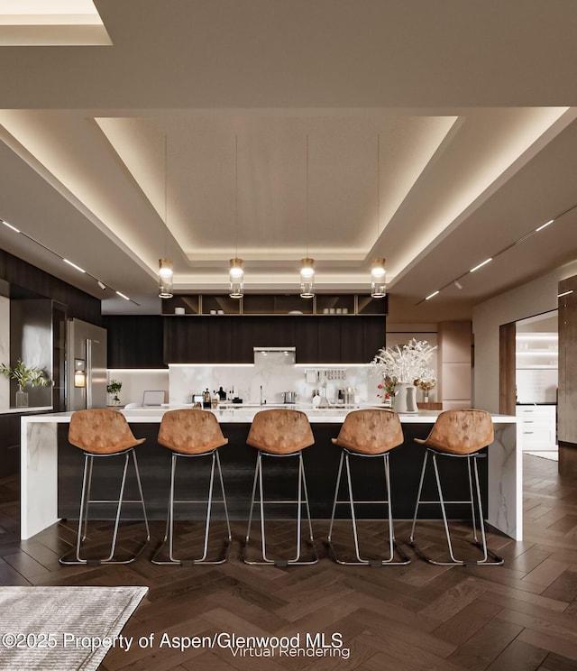 kitchen with a raised ceiling, a spacious island, high end refrigerator, and a breakfast bar area