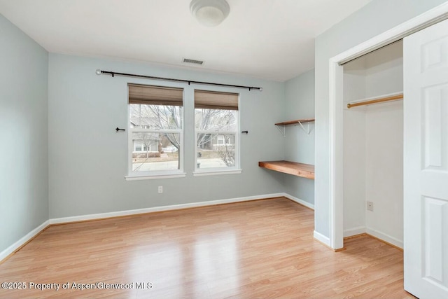 unfurnished bedroom featuring wood finished floors, visible vents, and baseboards