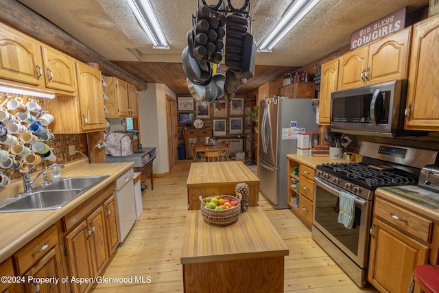 kitchen featuring wooden counters, stainless steel appliances, sink, a center island, and light hardwood / wood-style floors