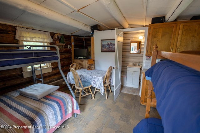 bedroom featuring ensuite bath, wooden walls, and sink