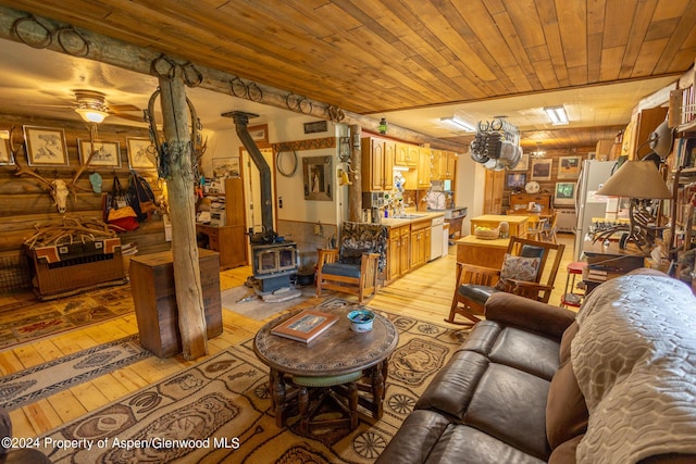 interior space featuring ceiling fan, light hardwood / wood-style floors, wood ceiling, and a wood stove