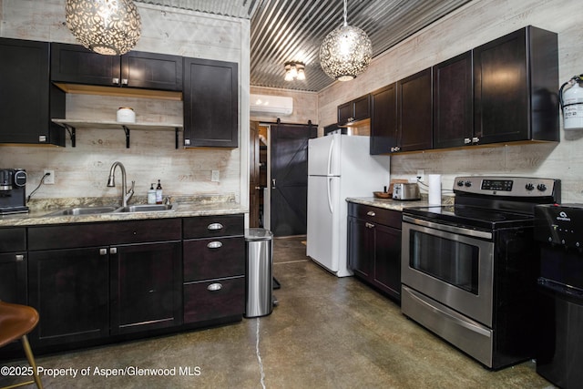 kitchen featuring a wall unit AC, a barn door, freestanding refrigerator, stainless steel range with electric cooktop, and a sink