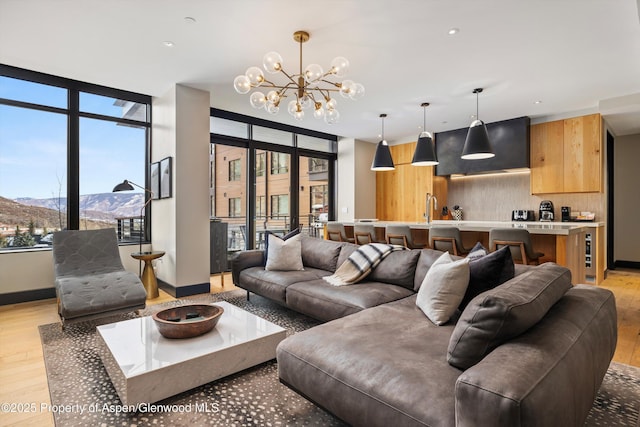 living room with a mountain view, a notable chandelier, light hardwood / wood-style flooring, and sink