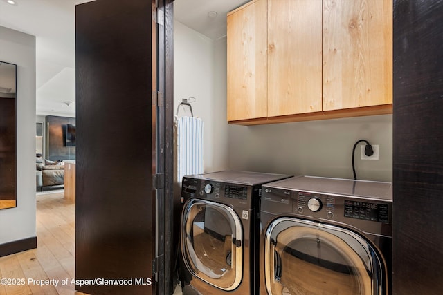 clothes washing area featuring cabinets, independent washer and dryer, and light hardwood / wood-style floors