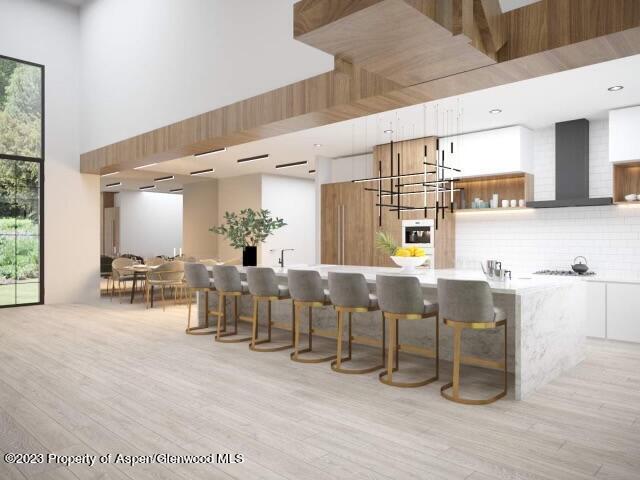 65 Upland Ln Unit 2, Carbondale, CO 81623 - kitchen with wall chimney exhaust hood, a high ceiling, backsplash, light wood-type flooring, and gas stovetop