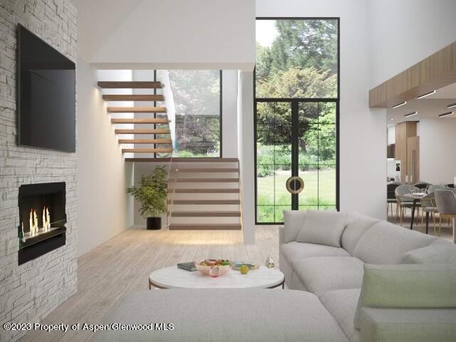 65 Upland Ln Unit 2, Carbondale, CO 81623 - living area featuring wood finished floors, stairs, a fireplace, a towering ceiling, and plenty of natural light