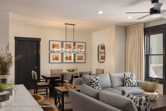 living room featuring ceiling fan with notable chandelier