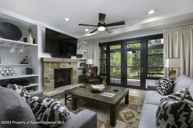 living room featuring ceiling fan, a stone fireplace, and built in features