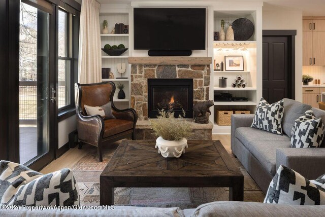 living room with a stone fireplace and light hardwood / wood-style flooring