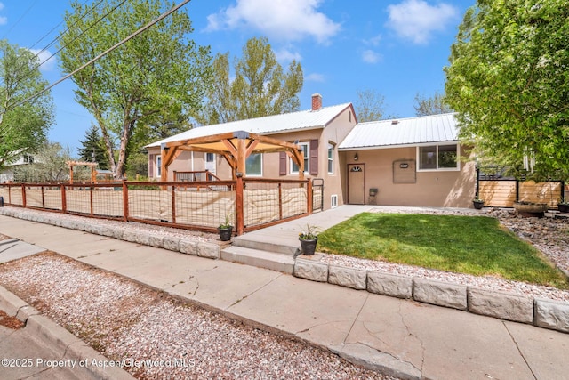 235 W 8th St, Craig, CO 81625 - view of front of house featuring stucco siding, metal roof, and a chimney