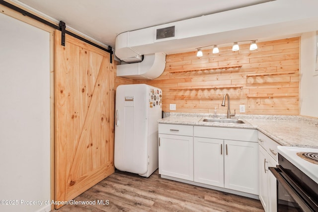 235 W 8th St, Craig, CO 81625 - kitchen with fridge, a sink, wooden walls, track lighting, and light wood finished floors