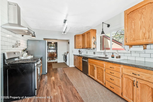 235 W 8th St, Craig, CO 81625 - kitchen featuring appliances with stainless steel finishes, wall chimney exhaust hood, a sink, and decorative backsplash