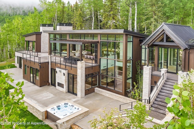 1234 Wood Rd, Snowmass Village, CO 81615 - rear view of property featuring an outdoor hot tub, stairs, a view of trees, a chimney, and a patio area