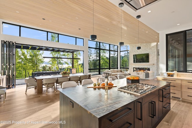 1234 Wood Rd, Snowmass Village, CO 81615 - kitchen featuring a towering ceiling, light wood-style floors, stainless steel gas stovetop, hanging light fixtures, and recessed lighting