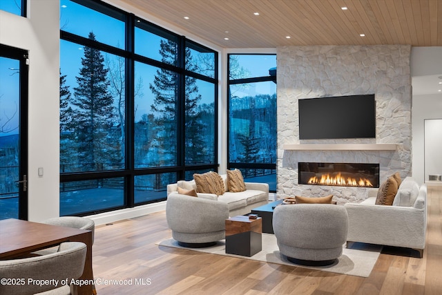 1234 Wood Rd, Snowmass Village, CO 81615 - living area with wooden ceiling, wood finished floors, a stone fireplace, recessed lighting, and a wall of windows