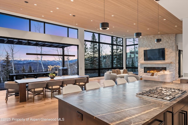 1234 Wood Rd, Snowmass Village, CO 81615 - kitchen with stainless steel countertops, light wood-style flooring, a stone fireplace, wood ceiling, and a high ceiling