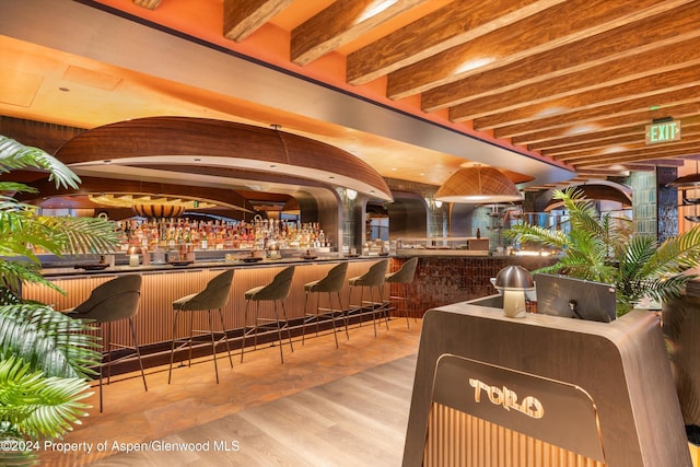 bar with beamed ceiling and light hardwood / wood-style flooring