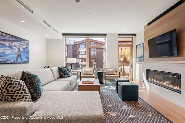 living room featuring a fireplace, dark wood-type flooring, and a wall of windows