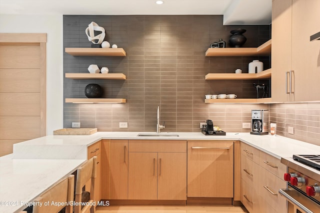 kitchen with stainless steel range, decorative backsplash, sink, and light brown cabinets