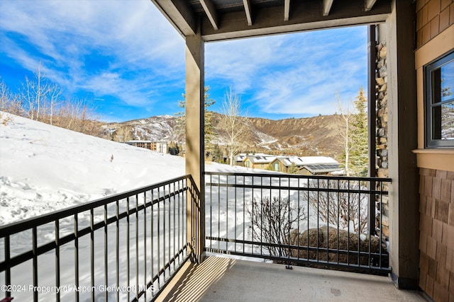 snow covered back of property featuring a mountain view