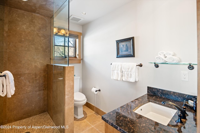 bathroom with a tile shower, sink, and toilet