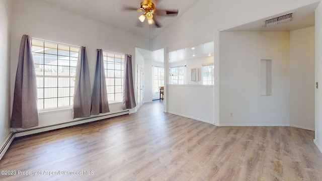 spare room featuring ceiling fan, light hardwood / wood-style flooring, high vaulted ceiling, and a baseboard heating unit