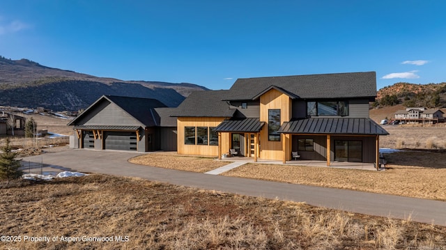 view of front of home featuring an attached garage, a standing seam roof, a mountain view, metal roof, and driveway