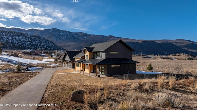 view of front facade featuring metal roof, a mountain view, a garage, covered porch, and a standing seam roof