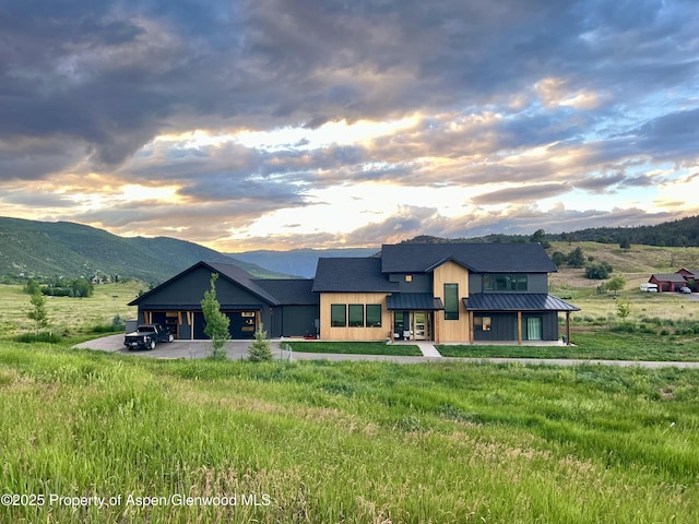 view of front facade with metal roof, a mountain view, roof with shingles, a standing seam roof, and a front yard