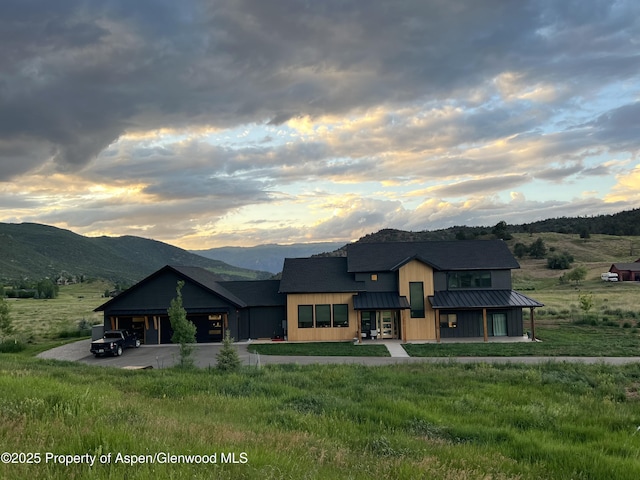 view of front of property with a standing seam roof, a mountain view, metal roof, and a yard