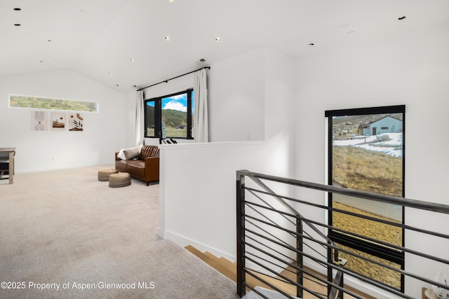 hall featuring carpet floors, baseboards, vaulted ceiling, and an upstairs landing