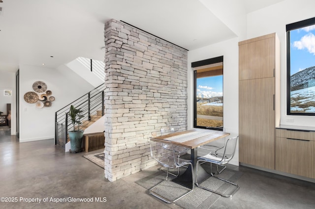 dining room with baseboards, concrete floors, and stairway