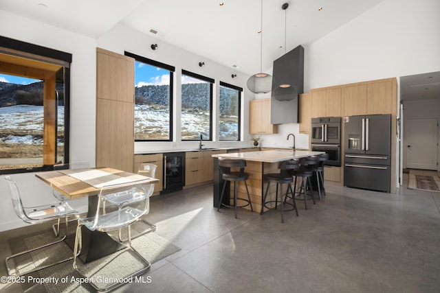 kitchen with beverage cooler, modern cabinets, a breakfast bar area, finished concrete floors, and stainless steel appliances