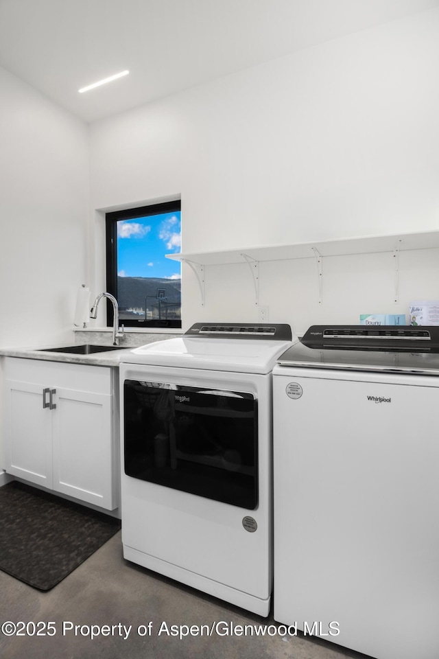 clothes washing area with washing machine and dryer, a sink, and cabinet space