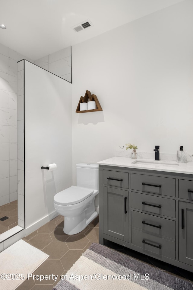 full bathroom featuring visible vents, toilet, a tile shower, vanity, and tile patterned floors