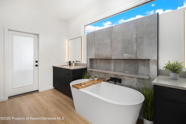 bathroom with a freestanding bath, wood finished floors, and vanity