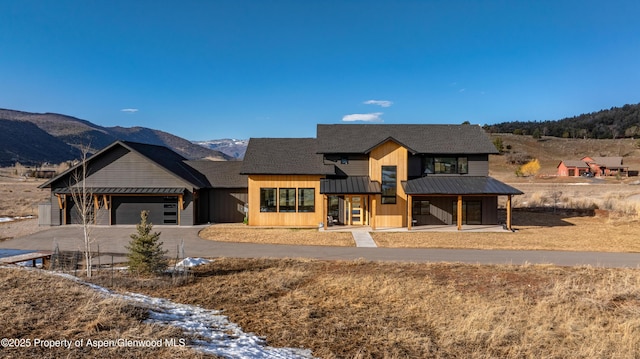 modern farmhouse style home with metal roof, a mountain view, a garage, concrete driveway, and a standing seam roof