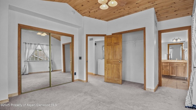 unfurnished bedroom featuring light carpet, wood ceiling, baseboards, vaulted ceiling, and washer / clothes dryer