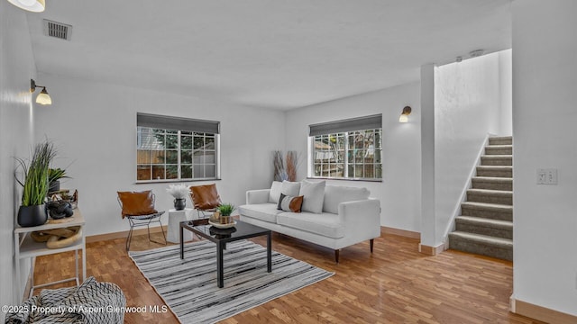 living area with stairs, wood finished floors, visible vents, and baseboards