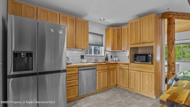 kitchen with decorative backsplash, butcher block counters, appliances with stainless steel finishes, light brown cabinets, and a sink