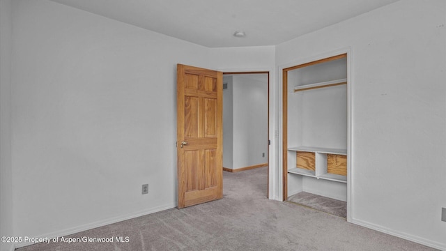 unfurnished bedroom featuring baseboards, a closet, and light colored carpet