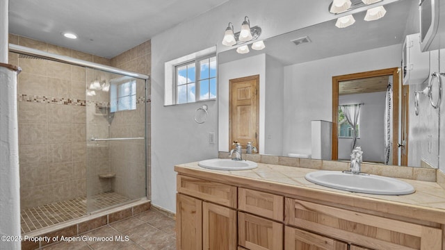 bathroom featuring tile patterned floors, a sink, visible vents, and a shower stall