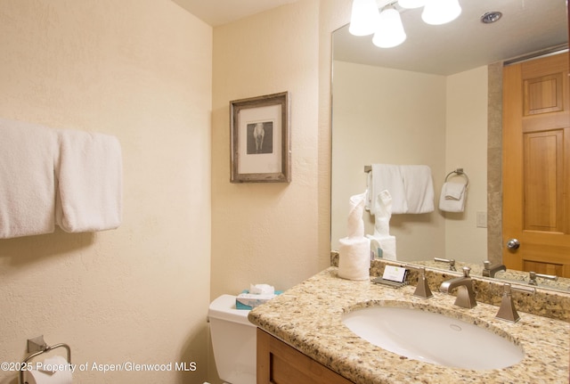 425 Wood Rd Unit 48, Snowmass Village, CO 81615 - half bath featuring vanity, toilet, a textured wall, and a chandelier