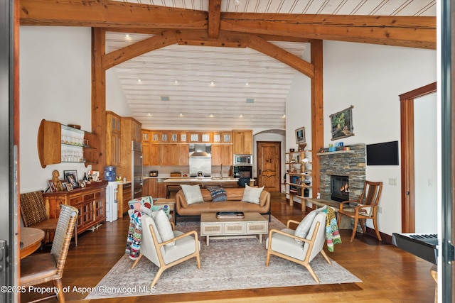 living area featuring beam ceiling, dark wood-style flooring, recessed lighting, a stone fireplace, and high vaulted ceiling